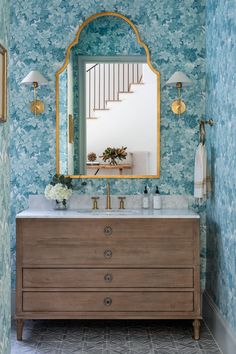 a bathroom with blue wallpaper and a mirror on the wall above the vanity area