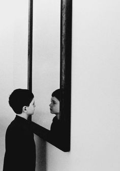 a woman standing in front of a mirror looking at her face in the mirror,