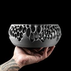 a hand holding a black and white object in front of a black background with lots of holes