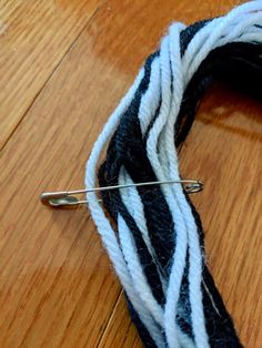 a close up of a piece of yarn on a wooden floor with a pin in it