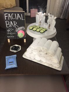 a table with towels and soaps on it in front of a sign that says facial bar