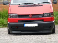 a red van is parked in front of a brick wall and green grass behind it