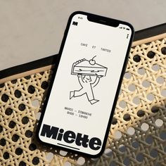 a cell phone sitting on top of a wooden table next to a white and black sign