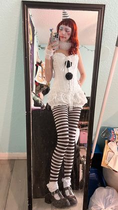 a woman dressed as a clown taking a selfie in a mirror