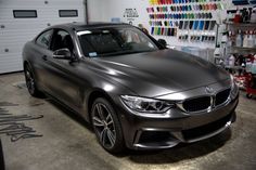 a silver car parked in a garage next to a wall full of paint cans and bottles