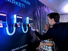 a man and woman standing next to a wall with cell phones attached to the side