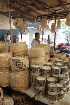 baskets are stacked on top of each other in front of a woman at an outdoor market