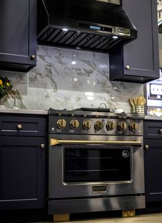 an oven and stove in a kitchen with marble counter tops, blue cabinets and gold accents
