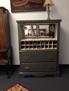 an old dresser with wine bottles on it and a man in the mirror behind it
