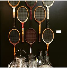 four tennis rackets are hanging on the wall next to cups and glasses in front of them