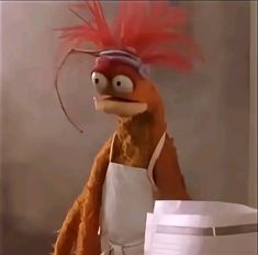 a stuffed bird wearing an apron and hat with red feathers on it's head