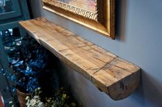 a wooden shelf sitting on the side of a wall next to a potted plant