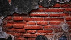 an old red brick wall with peeling paint and chipping off the edges, partially visible