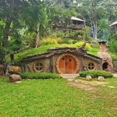 a hobbot house in the middle of a lush green field with trees and bushes