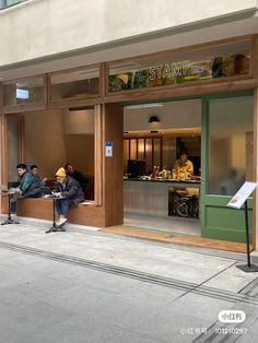 two men sitting on benches in front of a store