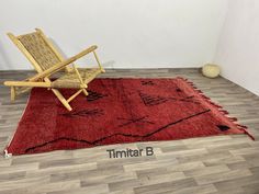 a chair sitting on top of a red rug next to a wooden chair with the word timita b written below it
