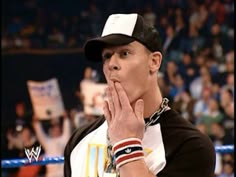 a man standing in front of a crowd with his hands clasped to his face while wearing a black and white hat
