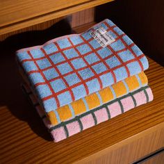two towels sitting on top of a wooden dresser next to a drawer with drawers in the background