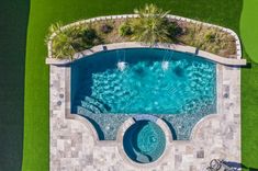 an aerial view of a swimming pool in the middle of a green lawn and grass area