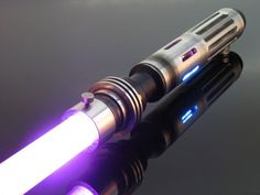 a close up of a light saber on a black surface with blue and white lights