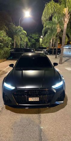 a black sports car parked on the street at night with its headlights turned on and headlamps glowing