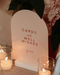 some candles are sitting on a table next to a card and well wishes sign