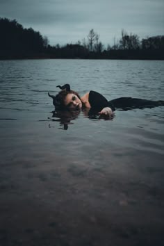 a woman floating on top of a body of water with her head above the water's surface
