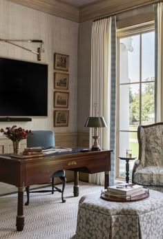 a living room filled with furniture and a flat screen tv mounted on the wall above a wooden desk