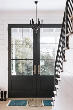 a black and white entryway with stairs leading up to the front door, next to a set of glass doors