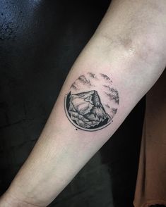 a man's arm with a mountain and clouds tattoo on the left inner forearm