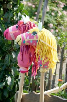 a pink horse with yellow manes on it's head and some flowers in the background