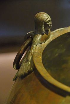 an antique brass vase with a figurine on top