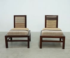 two wooden chairs sitting side by side on top of a cement floor next to each other