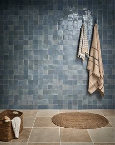towels hanging on the wall next to a basket and towel rack in a tiled bathroom