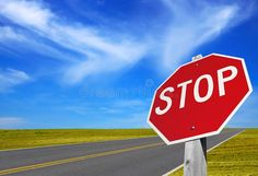 a red stop sign sitting on the side of a road in front of a blue sky