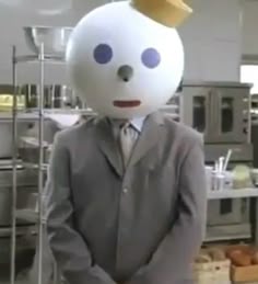 a man in a suit and hat standing next to a white ball with a gold crown on his head