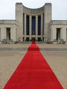 a red carpet is on the ground in front of a building with columns and pillars