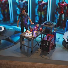 the action figure is on display in front of several other toys and accessories, including a table with two suitcases