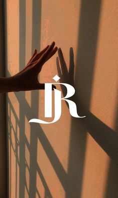 a person reaching out their hand to touch the wall in front of them, with the letter j on it