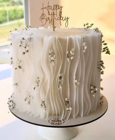 a birthday cake with white frosting and flowers on the top is sitting on a table