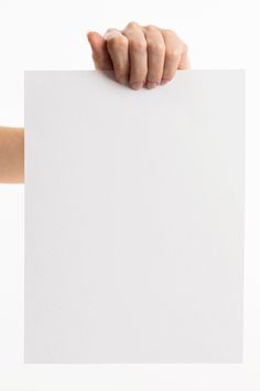 a person's hand holding up a white piece of paper against a white background