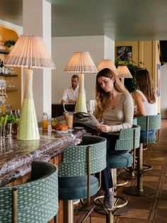 a woman sitting at a bar reading a magazine