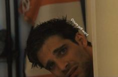 a man is looking at the camera while standing in front of an orange and white flag