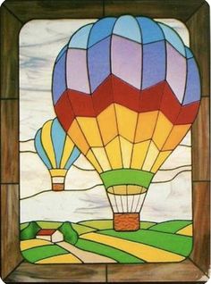 a colorful hot air balloon is in the sky above a green field and farm land