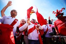 a group of men in red and white shirts holding up their hands while standing next to each other