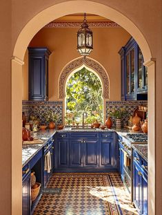 an archway leads into a kitchen with blue cabinets and checkered flooring on the walls