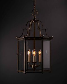 an old fashioned lantern hanging from the ceiling with three lit candles in front of it