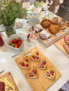 various pastries and desserts on wooden cutting boards sitting on a white counter top