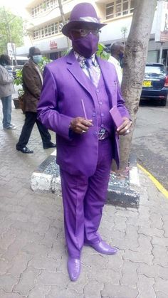a man in a purple suit is standing on the sidewalk