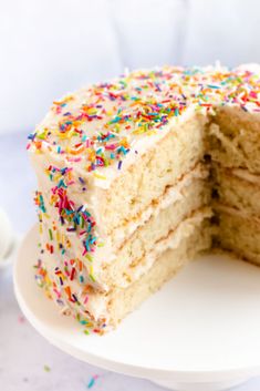 a cake with white frosting and sprinkles is cut from the plate